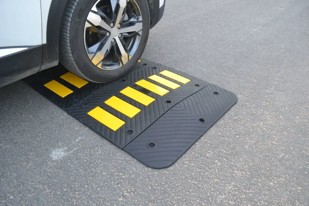 A black rubber speed hump with yellow reflective films to reduce speed.