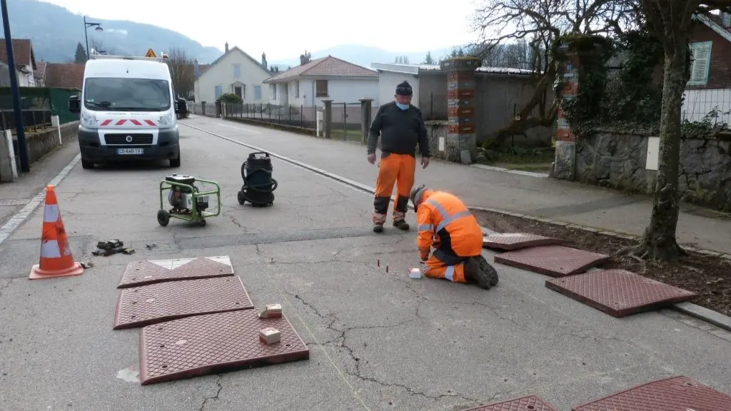 Two men are installing red road cushions.