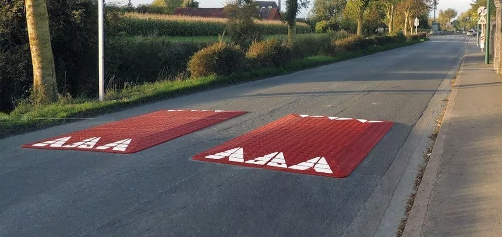 A pair of red Europe rubber speed cushions on the road as traffic-calming tools.