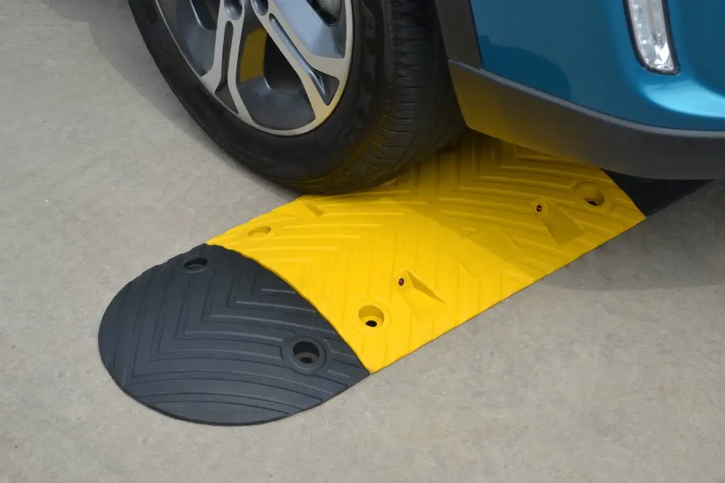 A black and yellow speed bump made of vulcanized rubber.