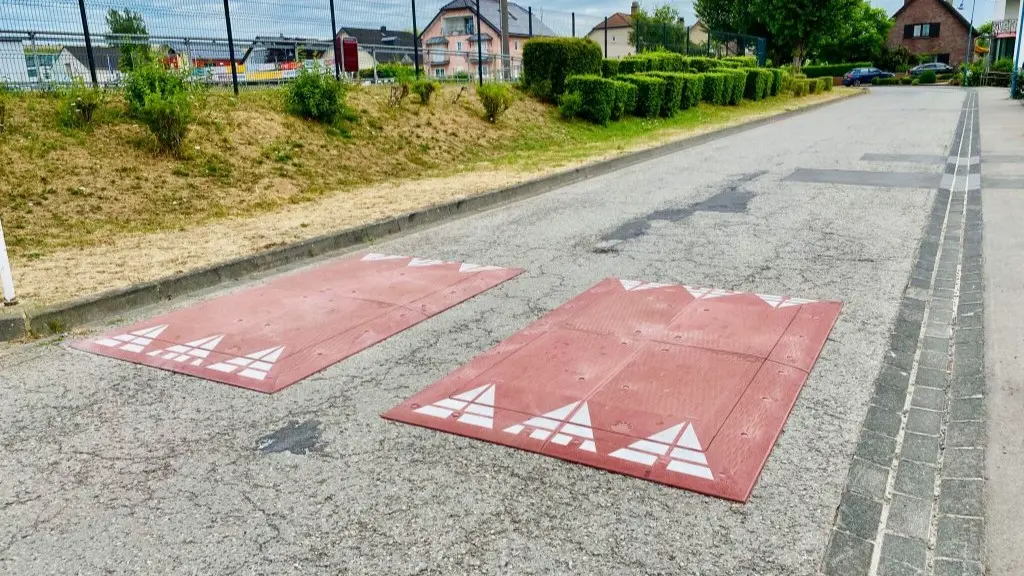 A pair of red rubber Europe speed cushions on the road for traffic-calming purposes.