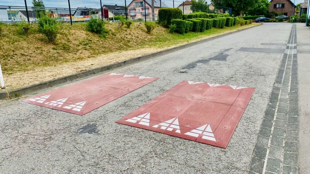 A pair of red speed cushions on the road.