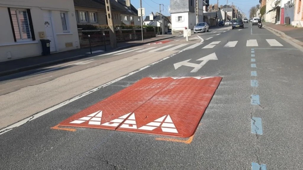 A red and white rubber speed cushion on the road to reduce speed.