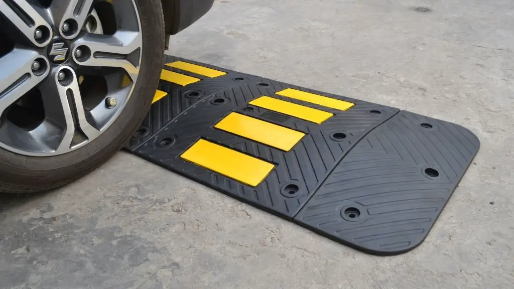 A black rubber speed hump with yellow reflective films.