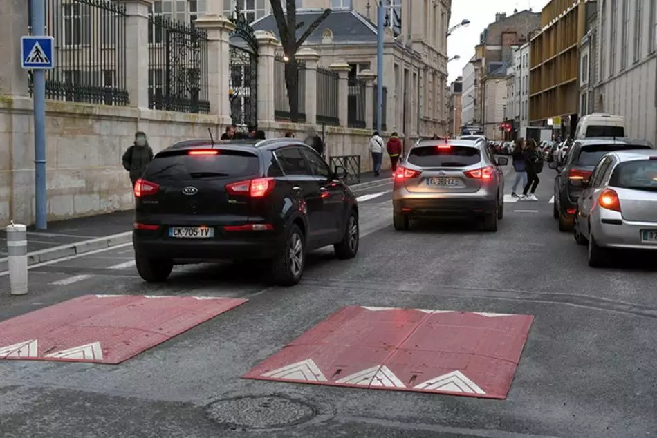 Two red Europe style traffic speed cushions on the road for traffic-calming purposes.