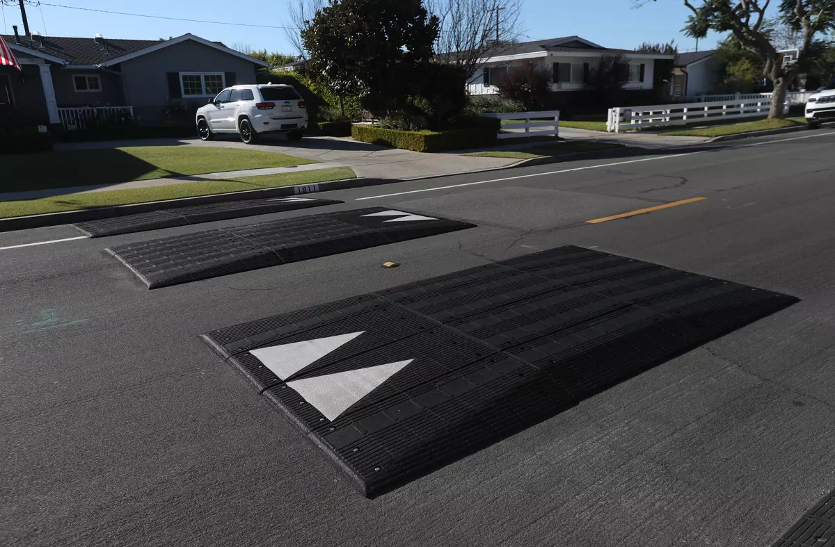 Black rubber speed cushions with white markings on the road as traffic-calming tools.